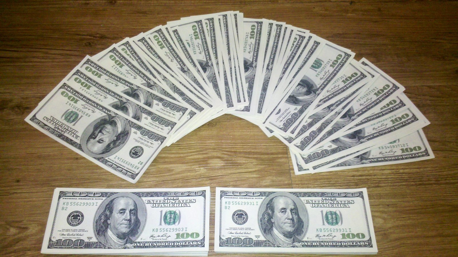 Fanned-out US hundred-dollar banknotes on a wooden table